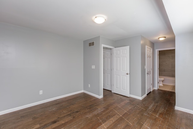 unfurnished bedroom with dark wood-style floors, visible vents, and baseboards