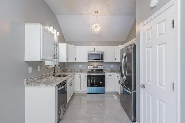 kitchen featuring lofted ceiling, stainless steel appliances, a sink, white cabinetry, and pendant lighting