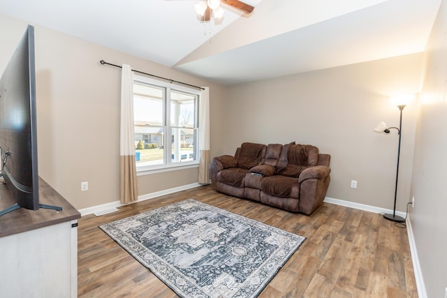 living area with ceiling fan, baseboards, vaulted ceiling, and wood finished floors