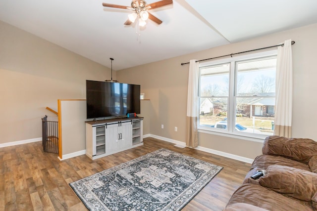 living area featuring lofted ceiling, a ceiling fan, baseboards, and wood finished floors