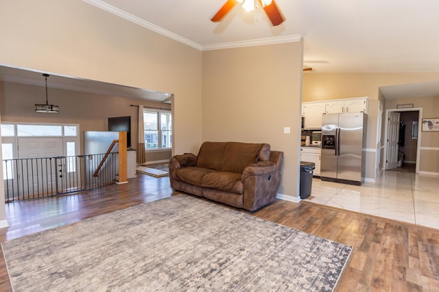 living room featuring ornamental molding, light wood-type flooring, vaulted ceiling, and baseboards