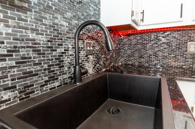 room details with dark countertops, a sink, and white cabinetry