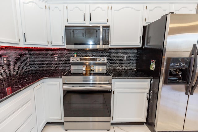 kitchen featuring appliances with stainless steel finishes, dark stone counters, white cabinetry, and tasteful backsplash