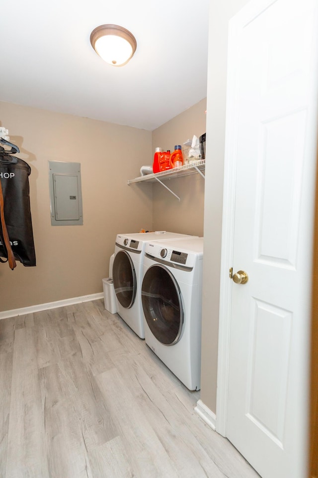 laundry area with laundry area, baseboards, light wood-style floors, electric panel, and washing machine and clothes dryer