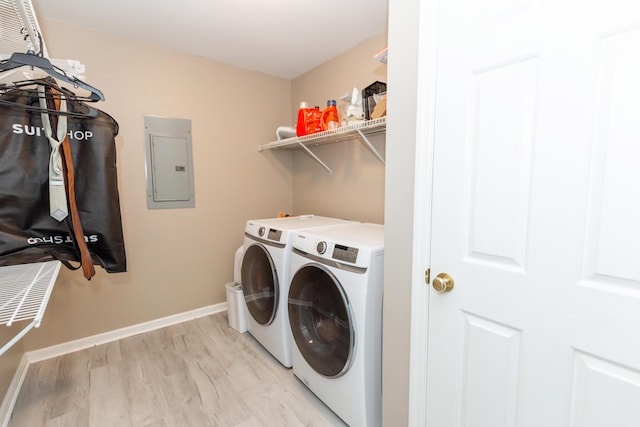 clothes washing area featuring laundry area, baseboards, electric panel, light wood finished floors, and washing machine and clothes dryer