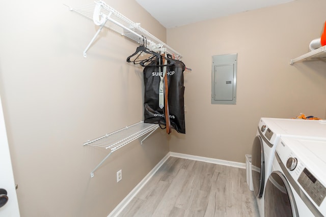 clothes washing area featuring separate washer and dryer, light wood-type flooring, laundry area, electric panel, and baseboards