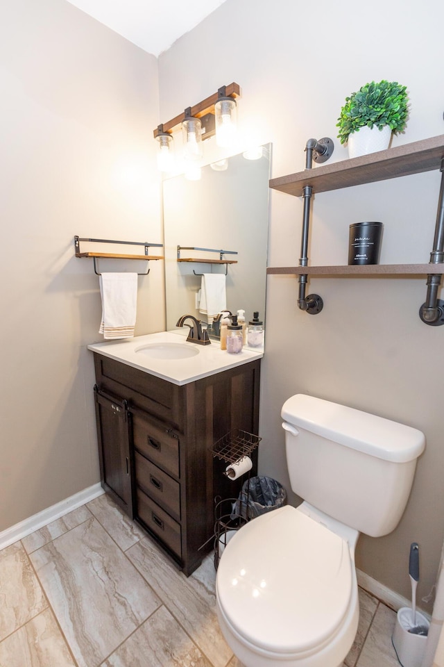 bathroom featuring toilet, marble finish floor, baseboards, and vanity