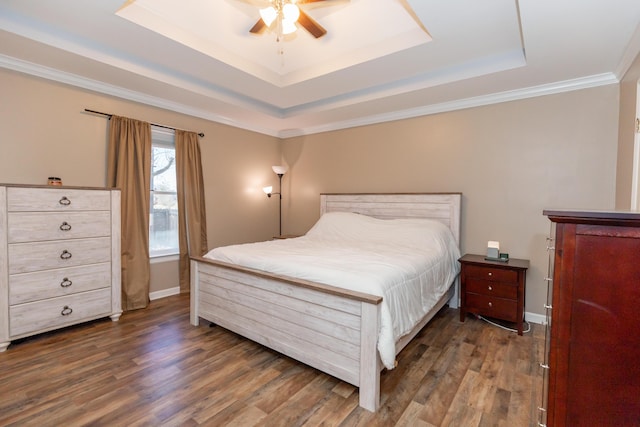 bedroom with crown molding, dark wood finished floors, a raised ceiling, ceiling fan, and baseboards