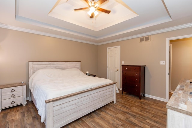 bedroom with dark wood-style flooring, a raised ceiling, visible vents, and baseboards