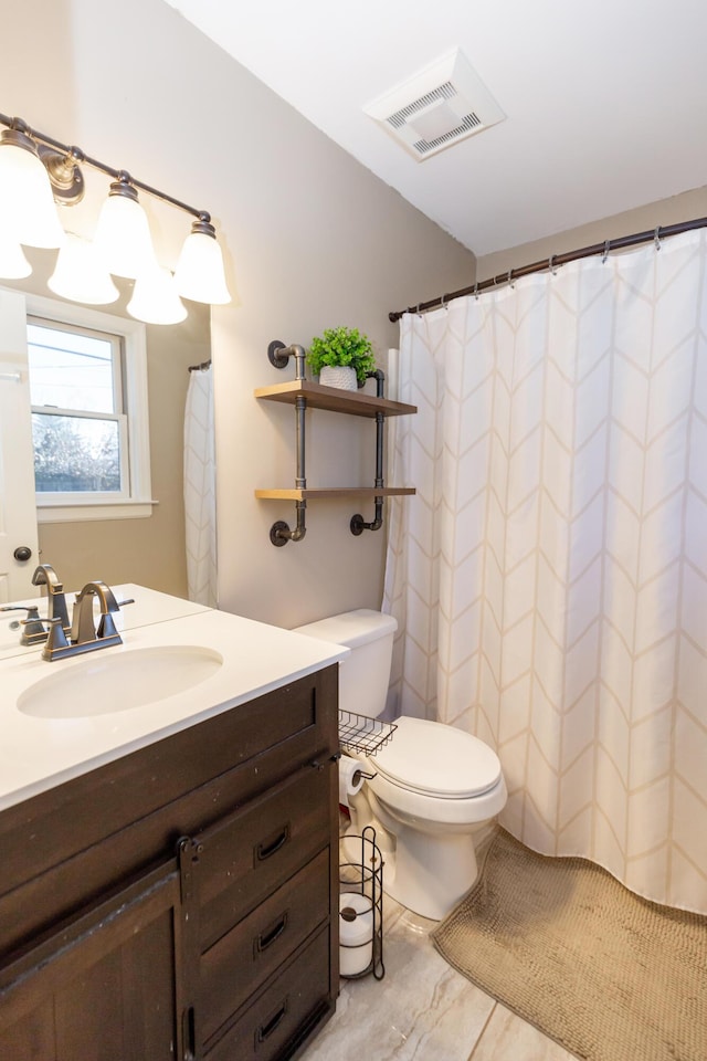 bathroom with toilet, vanity, and visible vents