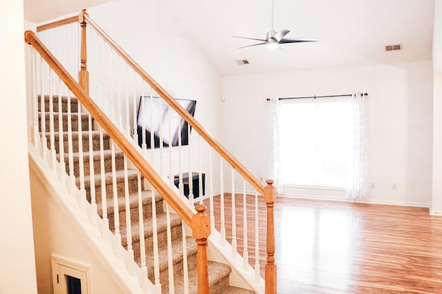 stairway featuring ceiling fan and wood-type flooring