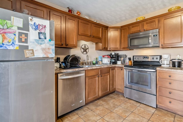 kitchen featuring stainless steel appliances, light tile patterned flooring, sink, and a textured ceiling