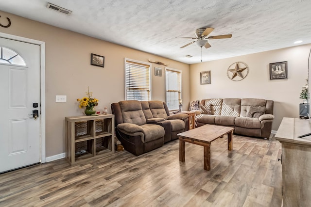 living room featuring ceiling fan, hardwood / wood-style floors, and a textured ceiling