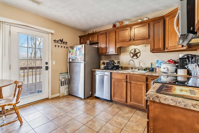 kitchen with light tile patterned flooring, appliances with stainless steel finishes, sink, and a textured ceiling