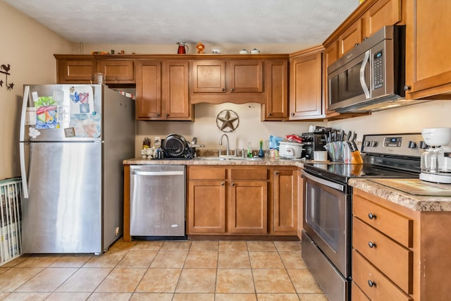 kitchen with appliances with stainless steel finishes, sink, and light tile patterned floors