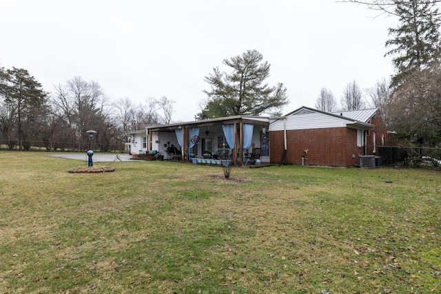 rear view of property with central AC unit and a lawn