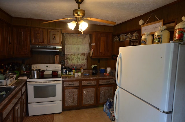 kitchen with ceiling fan, a textured ceiling, white appliances, and wood walls