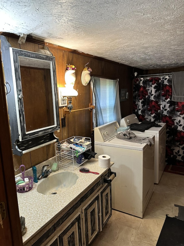 bathroom featuring vanity, a textured ceiling, washer and clothes dryer, and wood walls