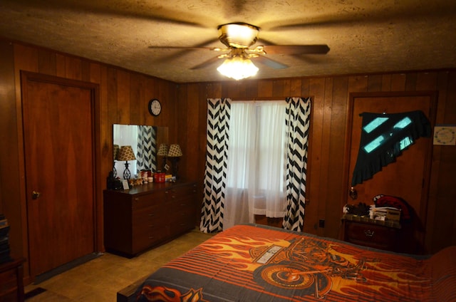 bedroom featuring a textured ceiling, ceiling fan, and wood walls