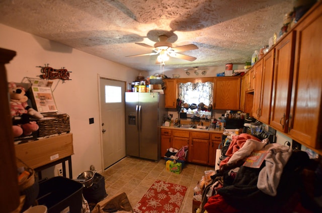 kitchen with ceiling fan, sink, a textured ceiling, and stainless steel refrigerator with ice dispenser