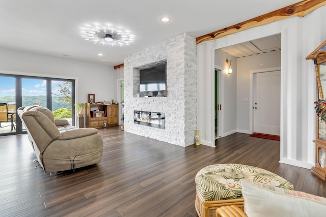 living room with dark wood-type flooring, a stone fireplace, and beam ceiling