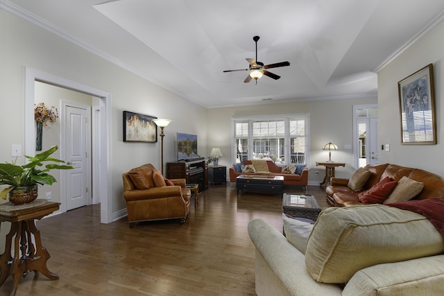 living room with a raised ceiling, crown molding, dark wood-type flooring, and ceiling fan