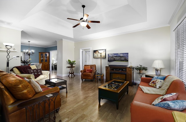 living room with a raised ceiling, ornamental molding, dark hardwood / wood-style floors, and ceiling fan with notable chandelier