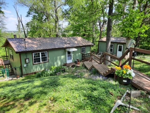 rear view of property with a lawn, an outdoor structure, and a wooden deck