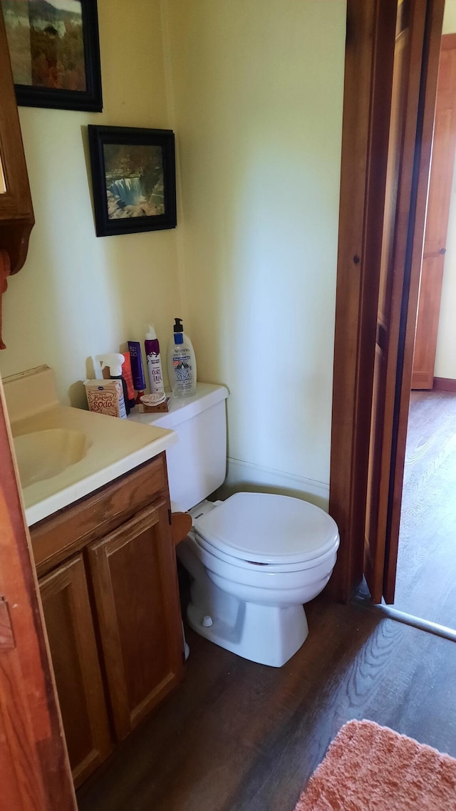 half bath featuring vanity, toilet, and wood finished floors