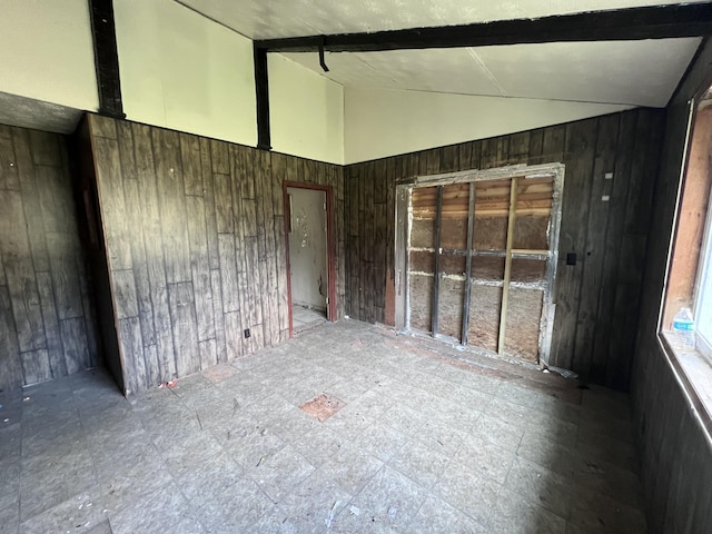 spare room featuring vaulted ceiling with beams and wood walls