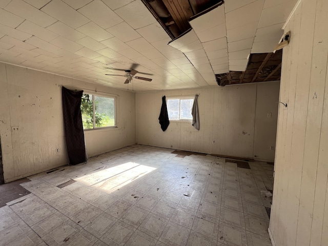 spare room with ceiling fan and wood walls