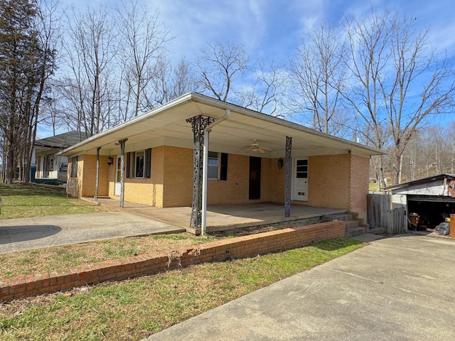 view of front of home with concrete driveway, brick siding, a ceiling fan, and an attached carport