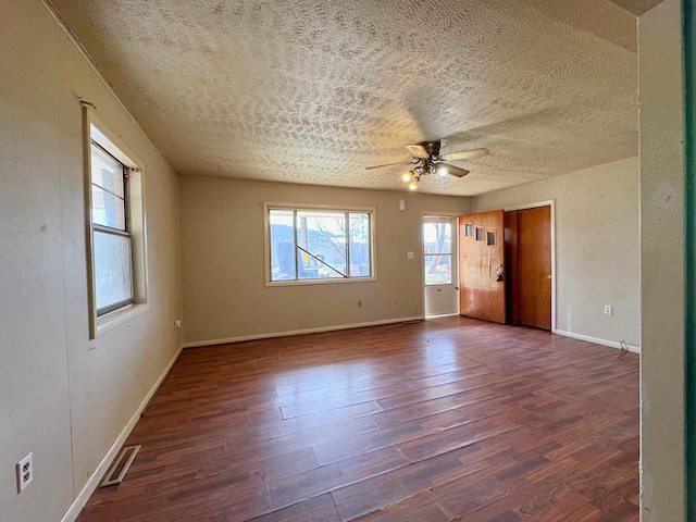 spare room with a textured ceiling, ceiling fan, and dark hardwood / wood-style floors