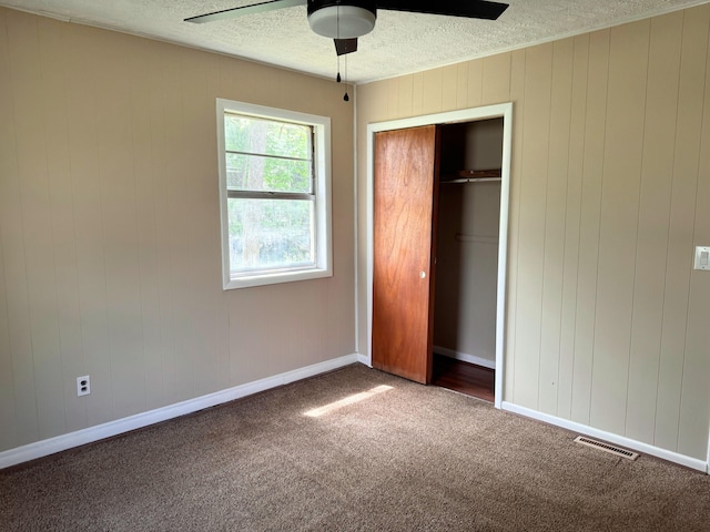 unfurnished bedroom with a closet, a textured ceiling, visible vents, carpet floors, and baseboards