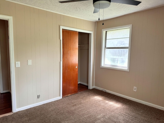 unfurnished bedroom with a textured ceiling, carpet floors, and a closet