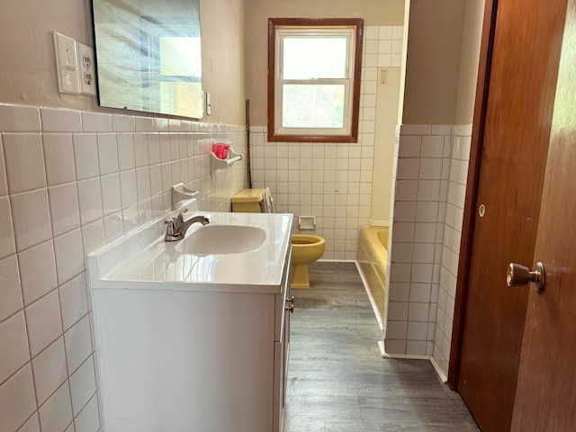 full bathroom featuring toilet, wood finished floors, tile walls, a tub, and vanity