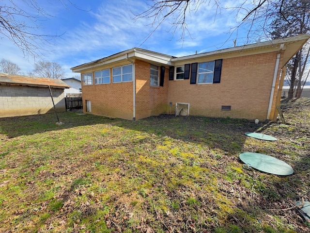 rear view of house with a lawn, fence, brick siding, and crawl space
