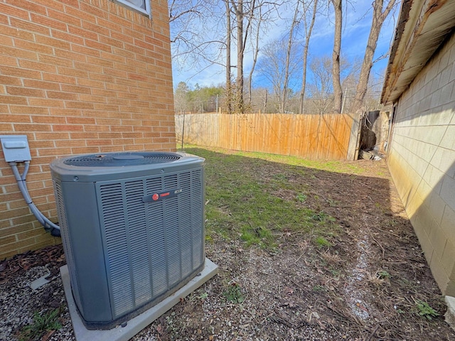 details with cooling unit, brick siding, and fence