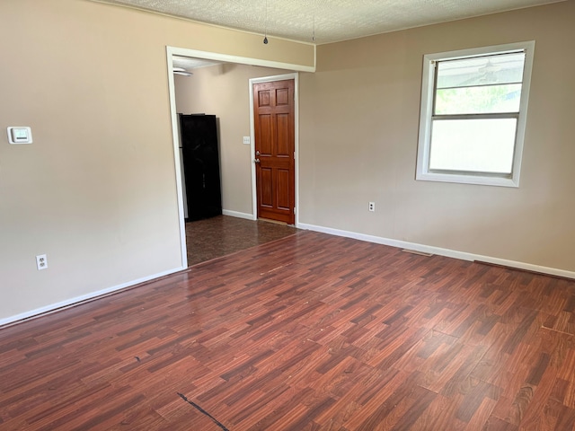 empty room featuring a textured ceiling, baseboards, and wood finished floors
