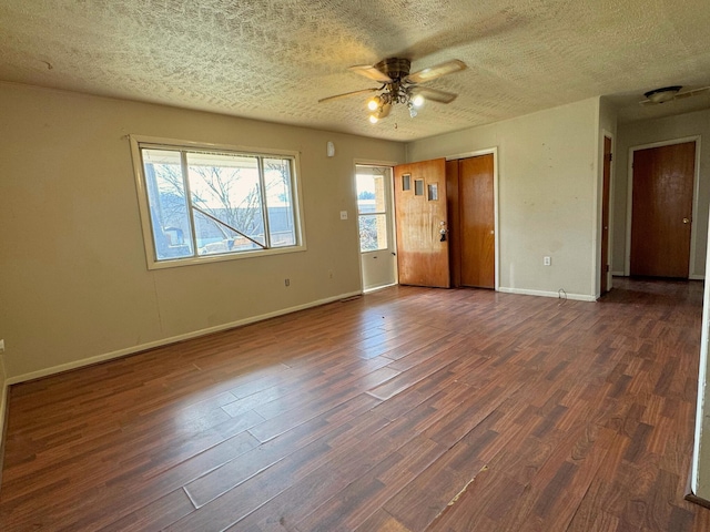 empty room with dark hardwood / wood-style flooring, ceiling fan, and a textured ceiling