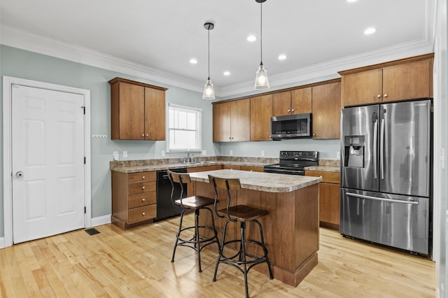 kitchen featuring light hardwood / wood-style flooring, black appliances, a kitchen island, and decorative light fixtures