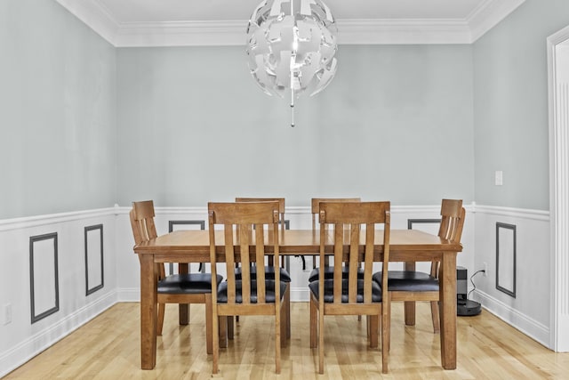 dining space with light hardwood / wood-style floors, crown molding, and a notable chandelier