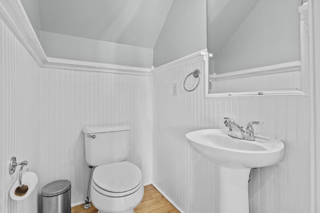 bathroom with hardwood / wood-style flooring, vaulted ceiling, sink, and toilet