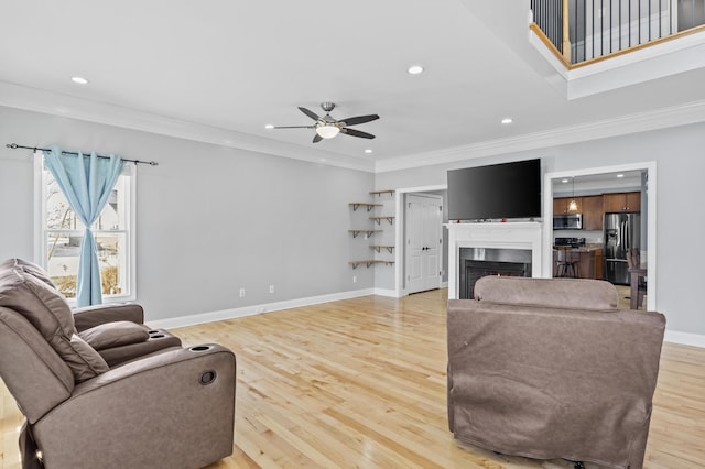 living room with ceiling fan, ornamental molding, and light hardwood / wood-style floors