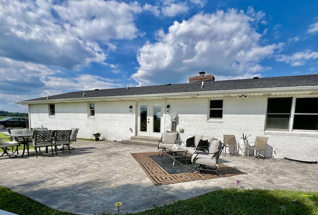back of property with french doors, a chimney, brick siding, and a patio