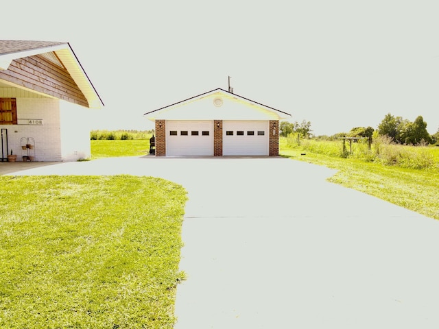 view of front of house featuring an outbuilding, a garage, a front lawn, and brick siding