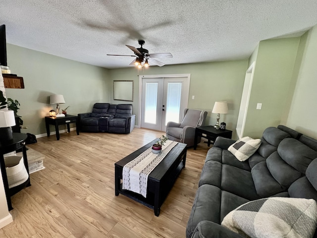 living room with a textured ceiling, light wood-style flooring, baseboards, ceiling fan, and french doors