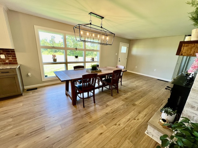dining room featuring baseboards, visible vents, a notable chandelier, and light wood-style floors