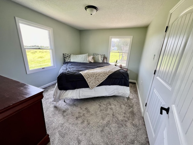 bedroom with carpet, baseboards, and a textured ceiling