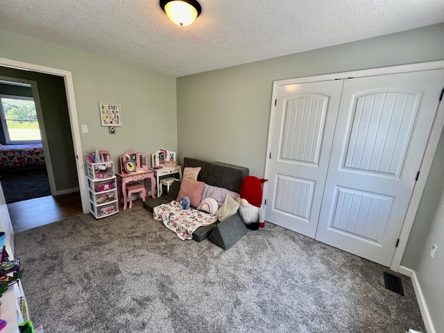 bedroom with carpet, baseboards, a textured ceiling, visible vents, and a closet
